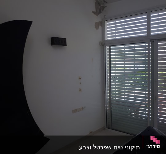 קיר עם קילופי צבע ליד חלון גדול